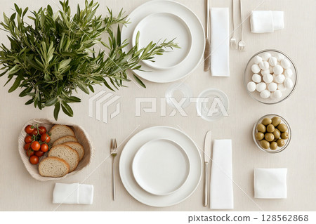 Elegant table setting with greenery, bread, olives, and mozzarella 128562868