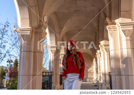 Woman Beret Arches: Elegant woman poses under arches outdoors in autumn sunlight for fashion shoot. Woman Beret Arches: Elegant woman poses under arches outdoors in autumn sunlight for fashion shoot. 128562955