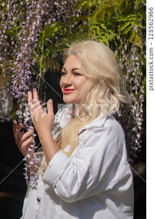 Wisteria Woman Portrait: Blonde woman poses with flowering Wisteria outdoors during the daytime for a spring photoshoot. Wisteria Woman Portrait: Blonde woman poses with flowering Wisteria outdoors during the daytime for a spring photoshoot. 128562966