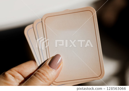 Hand holding a fan of blank playing cards in soft light, close-up of fingers and manicure Hand holding a fan of blank playing cards in soft light, close-up of fingers and manicure 128563066