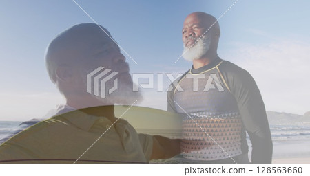 Composite of african american senior man stretching arms, and carrying surfboard on sunny beach 128563660