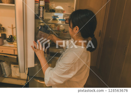 A housewife taking out the contents of the refrigerator A housewife taking out the contents of the refrigerator 128563676