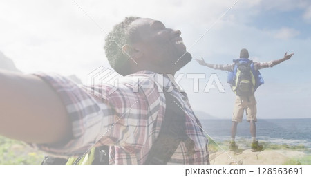 Composite of smiling african american man hiking on mountainside, standing with outstretched Composite of smiling african american man hiking on mountainside, standing with outstretched 128563691