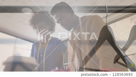 Composite of male and female clothes designers in studio, and clothes hangers on clothes rail 128563693