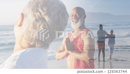 Composite of happy diverse senior couple doing yoga, and dancing on beach Composite of happy diverse senior couple doing yoga, and dancing on beach 128563744