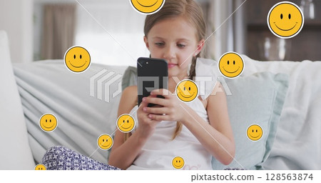 Image of smiley faces over happy caucasian girl using smartphone at home 128563874