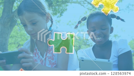 Image of colourful puzzle pieces over girls using tablets 128563974