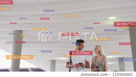 Image of social media icons floating over happy caucasian couple walking and using smartphones Image of social media icons floating over happy caucasian couple walking and using smartphones 128564002
