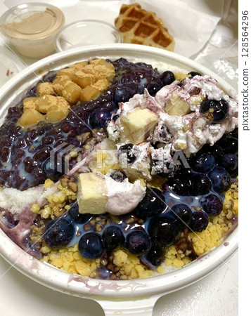 A refreshing bowl of bingsu, topped with fluffy shaved ice, vibrant fruits, and sweet toppings. Perfect for summer treats, this Korean dessert captures the essence of indulgence and delight. 128564296
