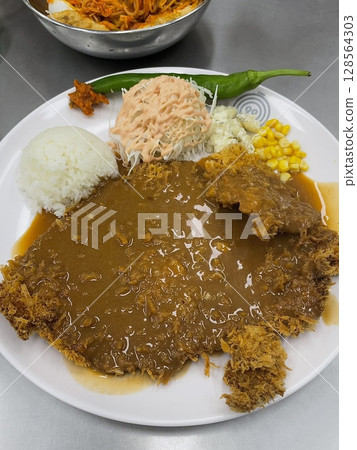 Crispy tonkatsu, a Japanese-style breaded and deep-fried pork cutlet, served with shredded cabbage and drizzled with savory sauce. A delightful balance of crunchy texture and juicy meat. 128564303