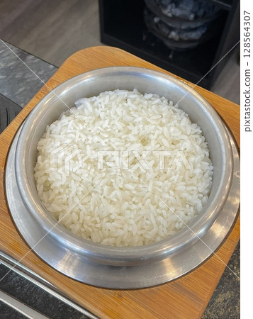 Steaming bowl of fluffy white rice, freshly cooked to perfection. Its delicate aroma and tender texture make it an ideal base for a variety of savory dishes. 128564307