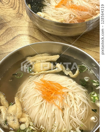 Janchi Guksu, a light and savory Korean noodle dish served in a clear broth, topped with vegetables, egg strips, and seaweed. A simple yet flavorful meal often enjoyed on special occasions. Janchi Guksu, a light and savory Korean noodle dish served in a clear broth, topped with vegetables, egg strips, and seaweed. A simple yet flavorful meal often enjoyed on special occasions. 128564319