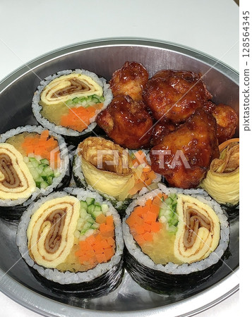 A delicious combination of kimbap and dakgangjeong. The crispy, sweet, and spicy Korean fried chicken pairs perfectly with the savory rice rolls, creating a flavorful and satisfying meal. 128564345