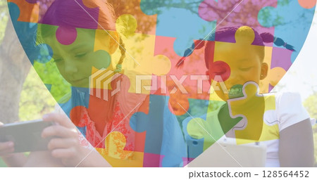 Image of colourful puzzle pieces heart over schoolgirls using tablets 128564452