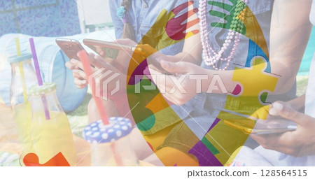 Image of colourful puzzle pieces ribbon over friends using smartphone and tablet 128564515