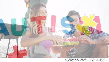 Image of colourful puzzle pieces heart and autism text over happy friends at summer beach party 128564516