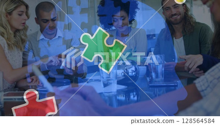 Image of colourful puzzle pieces over work colleagues using tablets 128564584