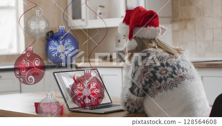 Image of christmas baubles over caucasian woman in santa hat on laptop image call at christmas Image of christmas baubles over caucasian woman in santa hat on laptop image call at christmas 128564608