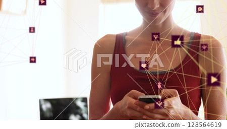 Image of network of connections with media icons over caucasian woman using smartphone 128564619