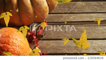 Image of orange autumn leaves falling over pumpkins 128564638