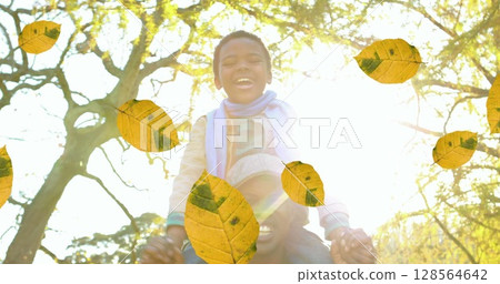 Image of orange autumn leaves falling over happy african american man and his son in park 128564642