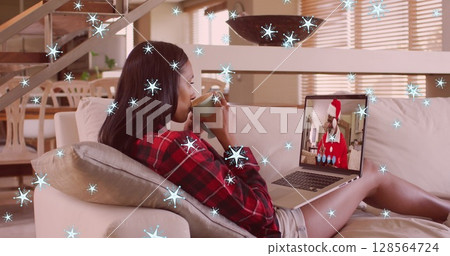 Image of snow falling over biracial woman on laptop image call with santa at christmas Image of snow falling over biracial woman on laptop image call with santa at christmas 128564724