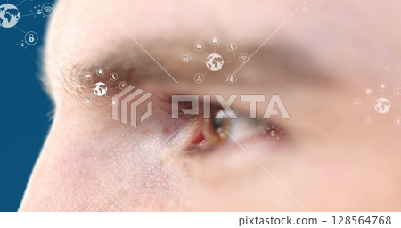 Image of icons over eye of caucasian man on blue background 128564768