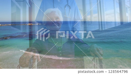 Image of caucasian senior woman on wheelchair and medic over seascape Image of caucasian senior woman on wheelchair and medic over seascape 128564796