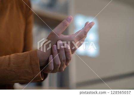 Wrist Pain Relief. Individual holding wrist, experiencing discomfort. 128565037