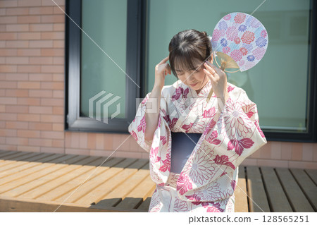 A woman in a yukata holding her head 128565251