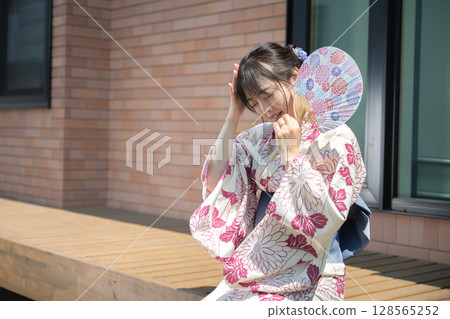 A woman in a yukata holding her head 128565252