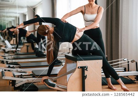 Teaching how to stretch spine. Women in fitness center are doing exercises 128565442