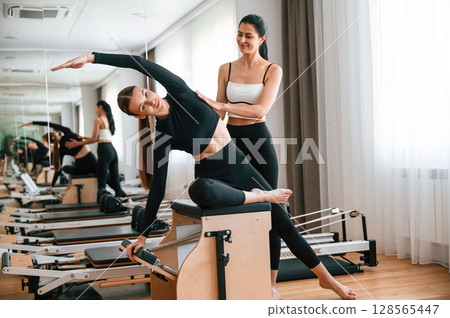 Personal trainer is controlling the process. Women in fitness center are doing exercises Personal trainer is controlling the process. Women in fitness center are doing exercises 128565447