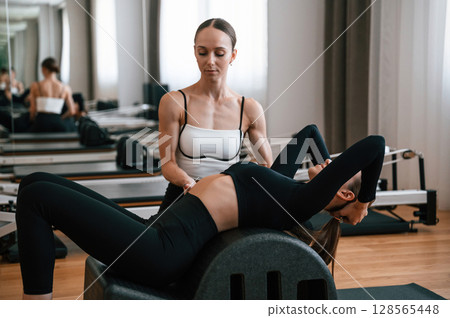 Personal trainer is controlling the process. Women in fitness center are doing exercises Personal trainer is controlling the process. Women in fitness center are doing exercises 128565448