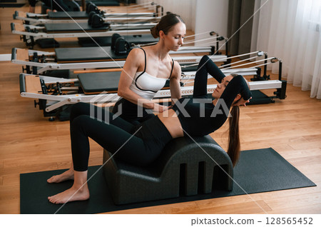 Trainer is helping with exercises. Women in fitness center Trainer is helping with exercises. Women in fitness center 128565452