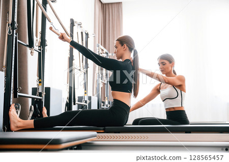 Trainer is helping with exercises. Women in fitness center 128565457