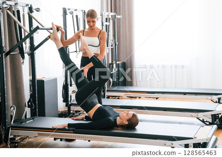 With legs up. Women in fitness center are doing exercises With legs up. Women in fitness center are doing exercises 128565463
