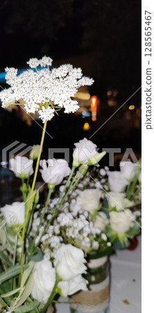 Rustic floral arrangement in jars. Festive decoration, white roses and plant branches in decorative jars. Rustic floral arrangement in jars. Festive decoration, white roses and plant branches in decorative jars. 128565467