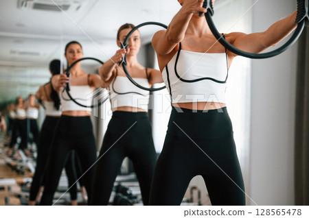 Three women in fitness center are doing exercises 128565478
