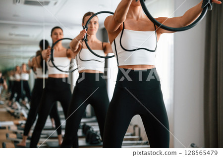 Three women in fitness center are doing exercises 128565479