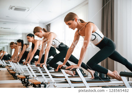 Doing push ups on the special device. Women in fitness center are doing exercises 128565482