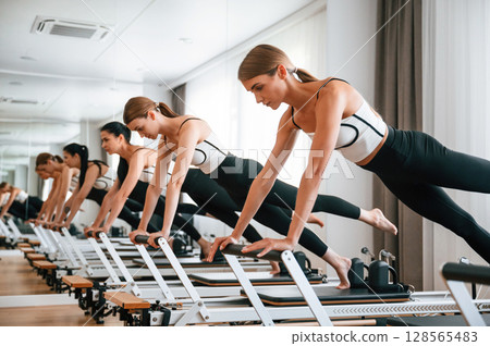 Doing push ups on the special device. Women in fitness center are doing exercises 128565483