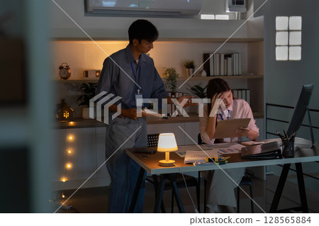 Guidance and Support. Young professional assisting a colleague with project tasks in a cozy office. 128565884
