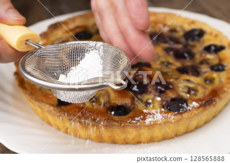 Cutting the baked fruit tart 128565888