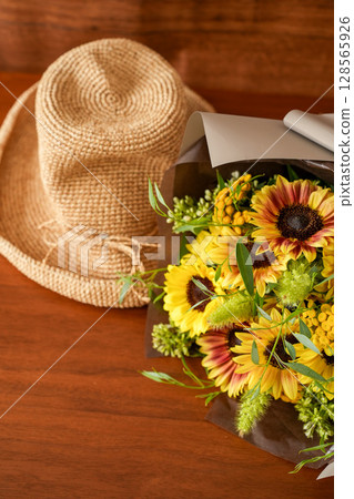 Sunflower arrangement and straw hat 128565926