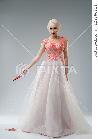 Bride in a blood-stained gown poses dramatically in studio setting 128566211