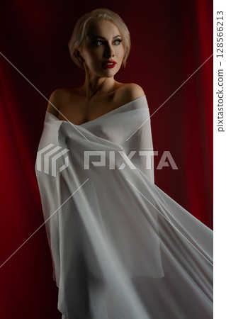 Elegant woman posing with flowing cloth in a studio setting 128566213