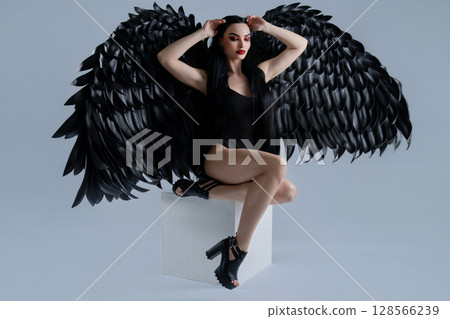 Elegance and allure of a woman in lingerie with striking black wings 128566239