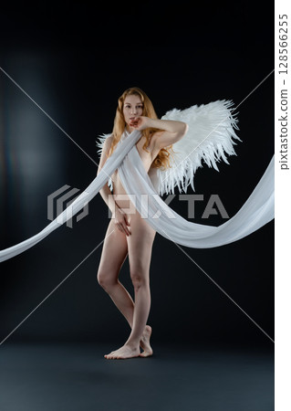 Red naked woman with angel wings showcases body art in studio setting Red naked woman with angel wings showcases body art in studio setting 128566255