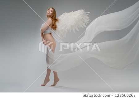 Red naked woman with angel wings posing gracefully in studio setting 128566262